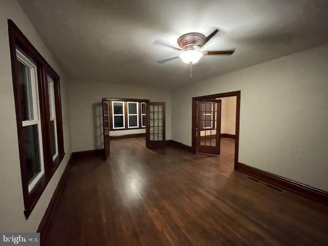 empty room featuring dark hardwood / wood-style floors, ceiling fan, and french doors