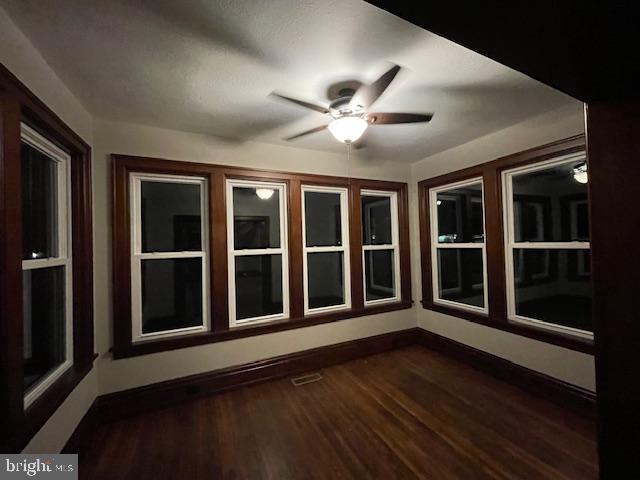 empty room with dark wood-type flooring and ceiling fan