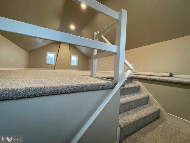 staircase with lofted ceiling and carpet floors