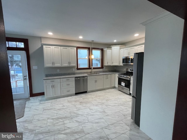 kitchen with stainless steel appliances, sink, white cabinets, and decorative light fixtures