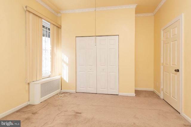 unfurnished bedroom featuring crown molding, a closet, radiator, and carpet