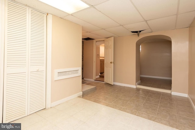 hallway with tile patterned floors and a drop ceiling