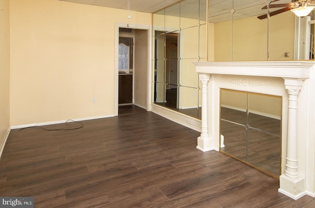 unfurnished living room featuring dark wood-type flooring and ceiling fan