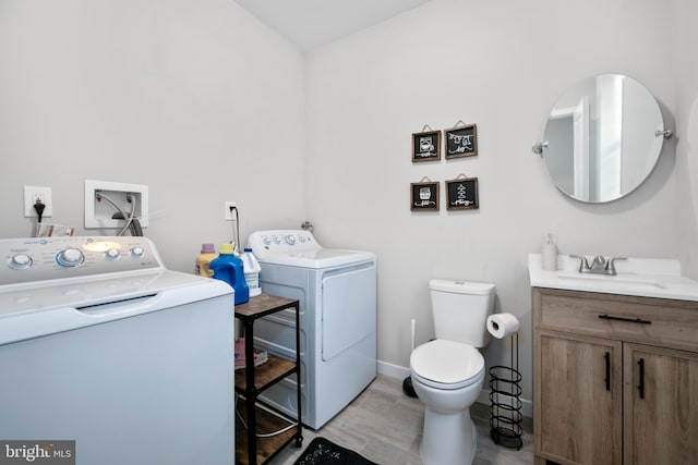 bathroom with washing machine and clothes dryer, vanity, toilet, and wood-type flooring