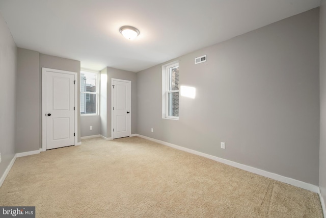 unfurnished bedroom featuring multiple windows and light colored carpet