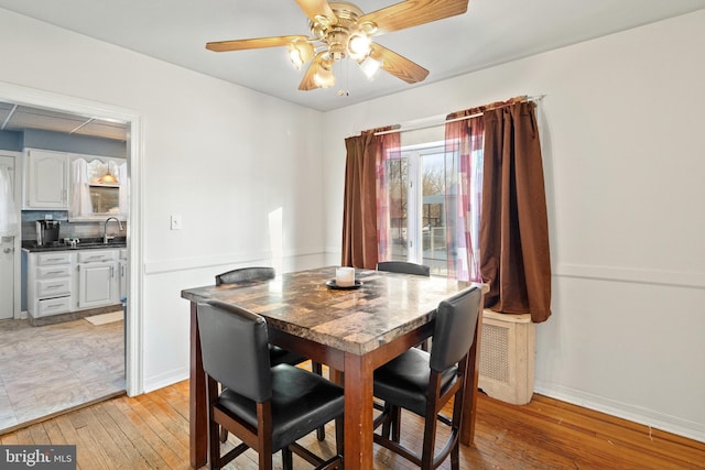 dining room featuring ceiling fan, sink, and light hardwood / wood-style flooring