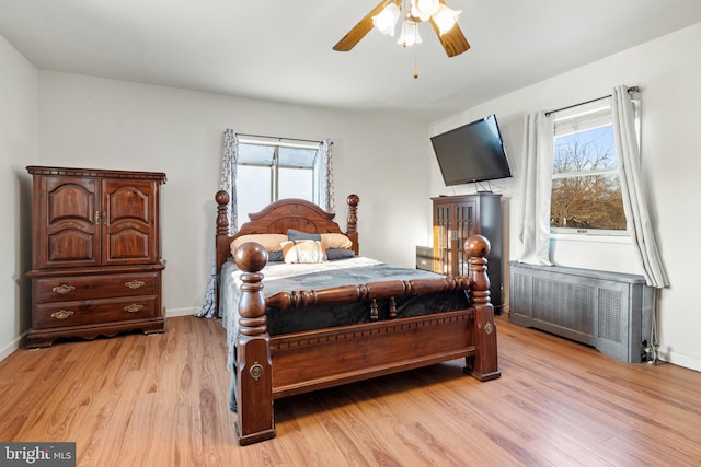 bedroom with ceiling fan, radiator heating unit, and light hardwood / wood-style flooring