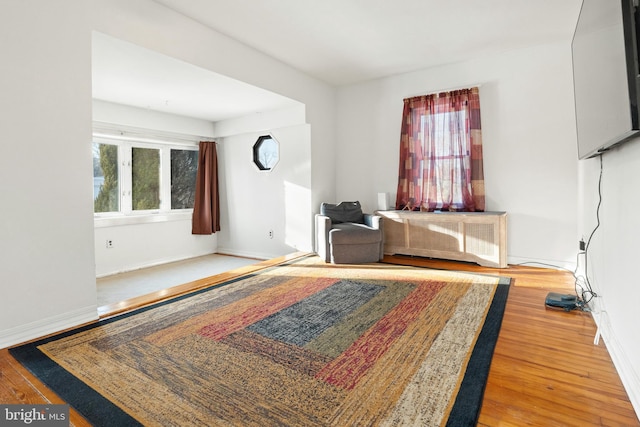 sitting room featuring radiator heating unit, wood-type flooring, and plenty of natural light