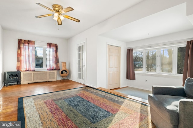 sitting room featuring hardwood / wood-style flooring, radiator, a wood stove, and ceiling fan