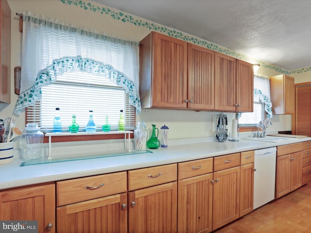 kitchen featuring sink, light parquet floors, a textured ceiling, and dishwasher