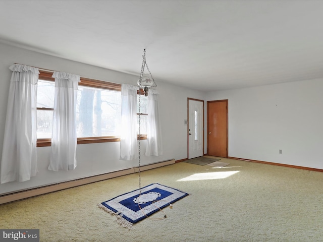 spare room featuring a baseboard heating unit and carpet floors