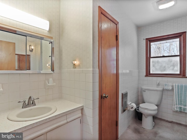 bathroom featuring vanity, toilet, and tile walls