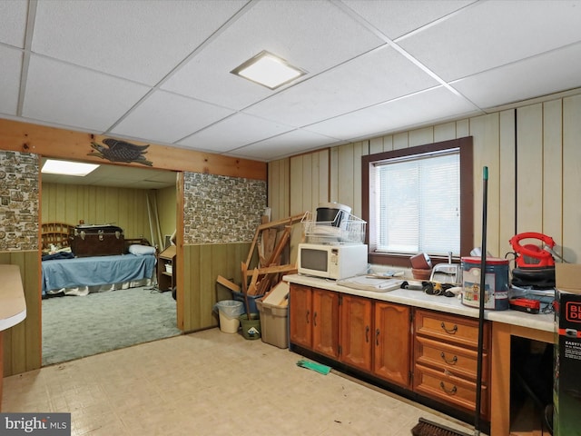 kitchen with a paneled ceiling and wooden walls