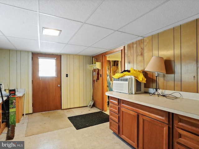 interior space featuring a drop ceiling and wood walls