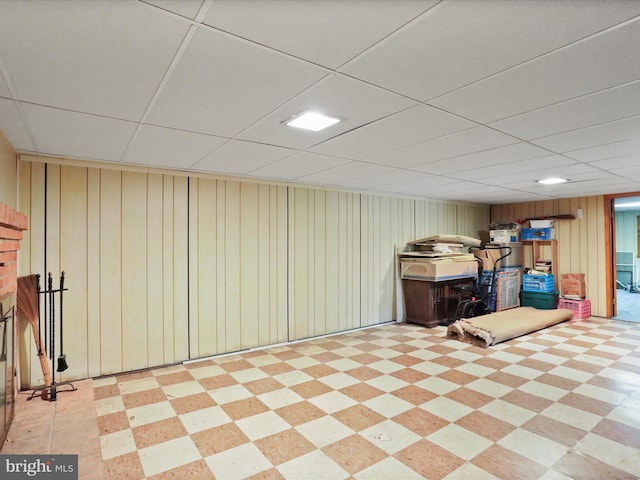 basement with a drop ceiling and wood walls