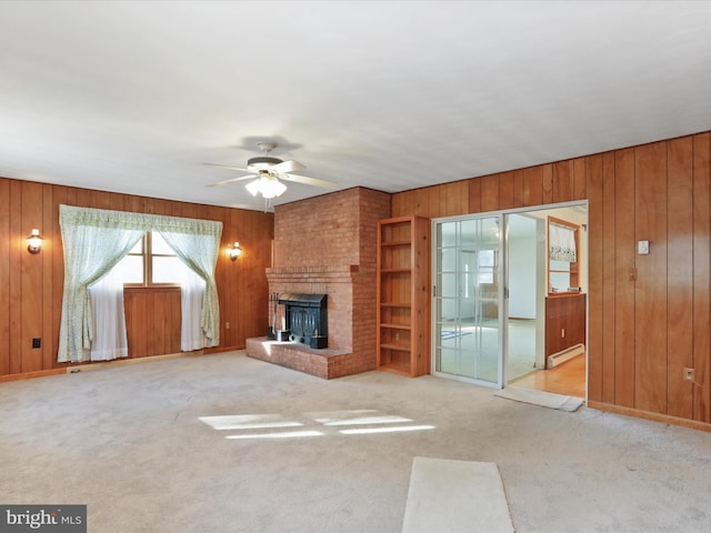 unfurnished living room with light colored carpet, a brick fireplace, wooden walls, ceiling fan, and a baseboard heating unit