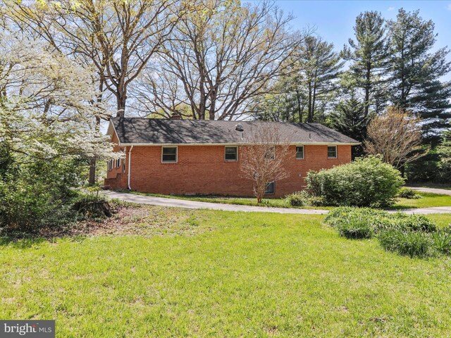 rear view of house featuring a lawn, brick siding, and a chimney