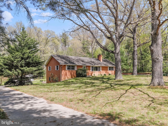 ranch-style house with brick siding, a front yard, and a chimney
