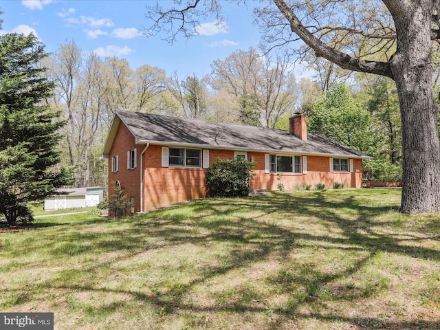 view of front of house featuring a chimney, brick siding, and a front yard