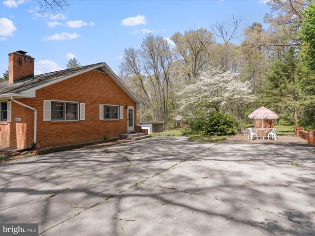 view of side of home with brick siding, a patio area, and a chimney