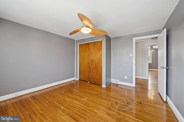 unfurnished bedroom featuring ceiling fan, wood-type flooring, and a closet