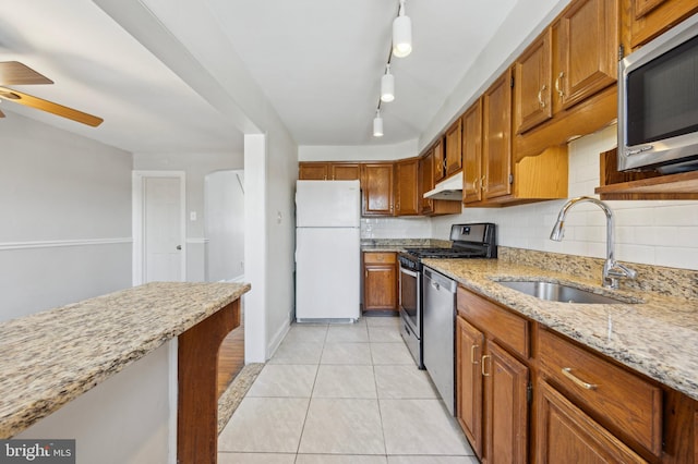 kitchen with sink, appliances with stainless steel finishes, tasteful backsplash, light stone countertops, and light tile patterned flooring