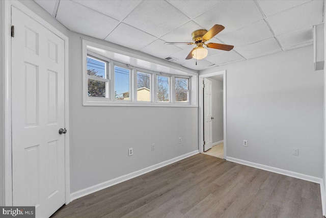 empty room with ceiling fan, a paneled ceiling, and wood-type flooring