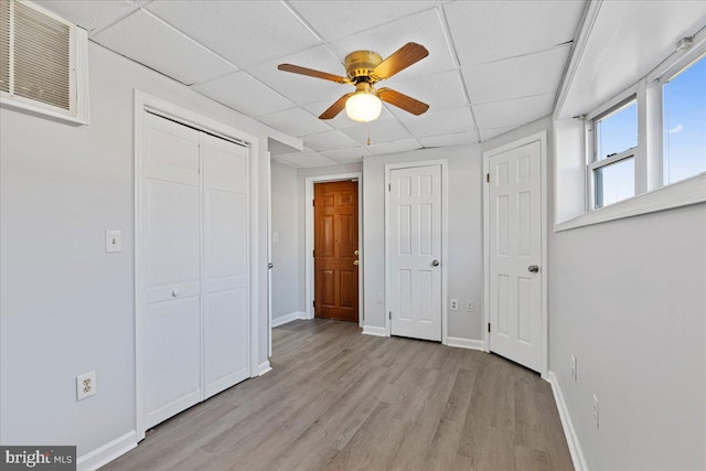 unfurnished bedroom featuring ceiling fan, a paneled ceiling, and light hardwood / wood-style flooring