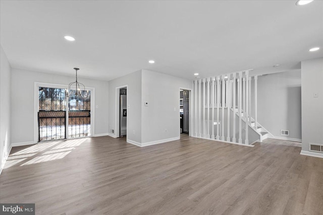 unfurnished living room with a chandelier and light wood-type flooring