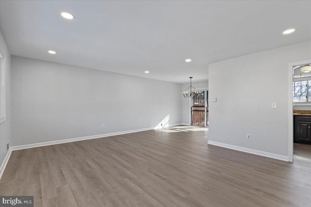 unfurnished living room with hardwood / wood-style flooring and a notable chandelier