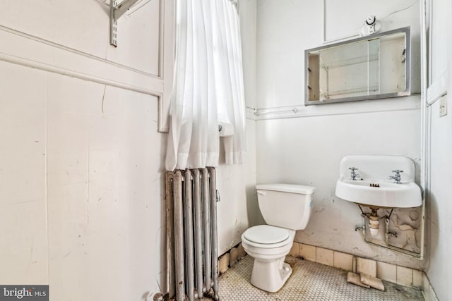 bathroom featuring tile patterned flooring, radiator, sink, and toilet