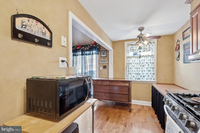 kitchen featuring ceiling fan, stainless steel gas range, and light wood-type flooring