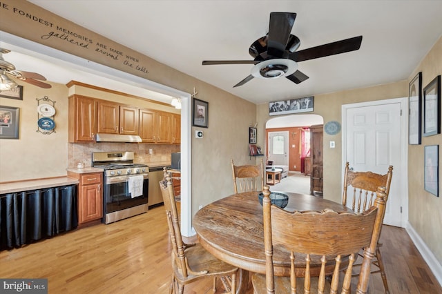 kitchen with light hardwood / wood-style flooring, backsplash, stainless steel gas range oven, and ceiling fan