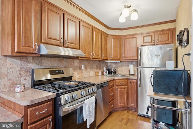 kitchen featuring sink, crown molding, stainless steel appliances, tasteful backsplash, and light wood-type flooring