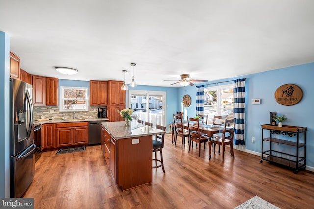 kitchen featuring decorative light fixtures, tasteful backsplash, black dishwasher, a center island, and stainless steel fridge with ice dispenser