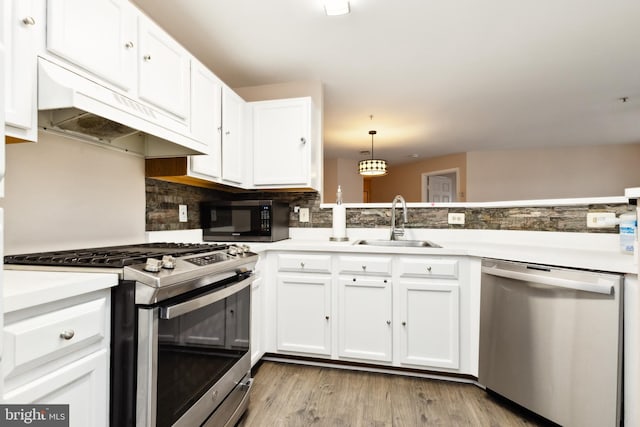 kitchen with decorative light fixtures, tasteful backsplash, white cabinetry, sink, and stainless steel appliances