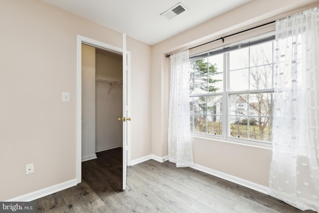 unfurnished bedroom with a walk in closet, wood-type flooring, and a closet