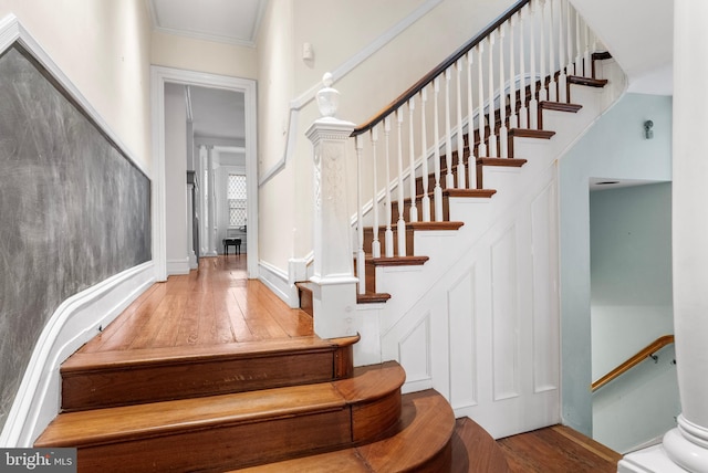 staircase featuring ornamental molding and wood finished floors