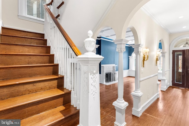 entryway with arched walkways, stairs, ornamental molding, hardwood / wood-style floors, and decorative columns