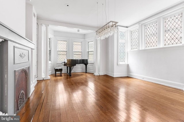 interior space featuring ornate columns, wood-type flooring, and baseboards