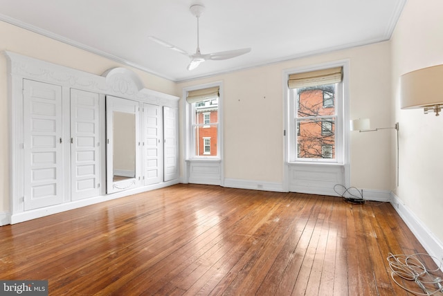 interior space featuring baseboards, hardwood / wood-style flooring, a wealth of natural light, and crown molding