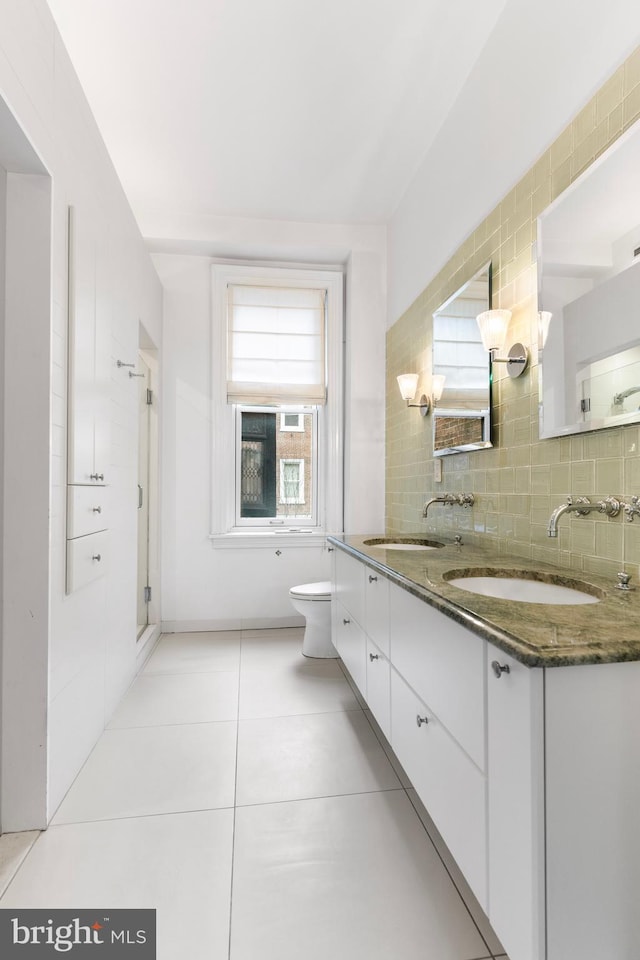 full bath featuring toilet, tasteful backsplash, a sink, and tile patterned floors