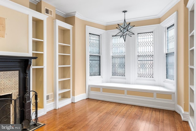 unfurnished dining area with hardwood / wood-style flooring, an inviting chandelier, visible vents, and crown molding