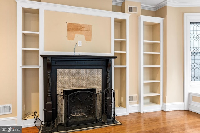 details with a tile fireplace, visible vents, and wood finished floors