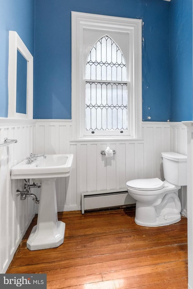 bathroom featuring toilet, a wainscoted wall, a baseboard radiator, and wood finished floors