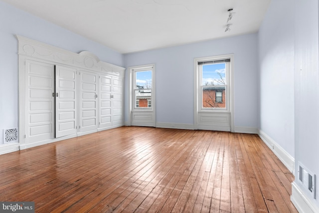 unfurnished bedroom featuring visible vents, baseboards, and hardwood / wood-style flooring