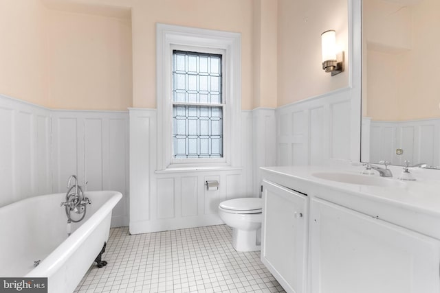 bathroom with a freestanding tub, a wainscoted wall, vanity, and toilet