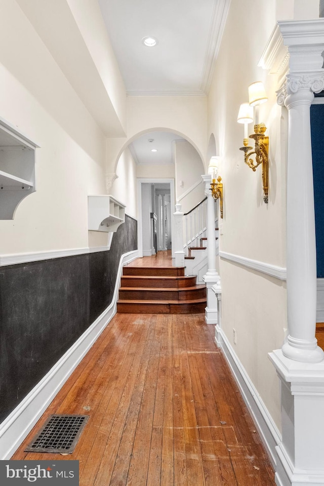 hall with visible vents, hardwood / wood-style flooring, stairs, crown molding, and ornate columns