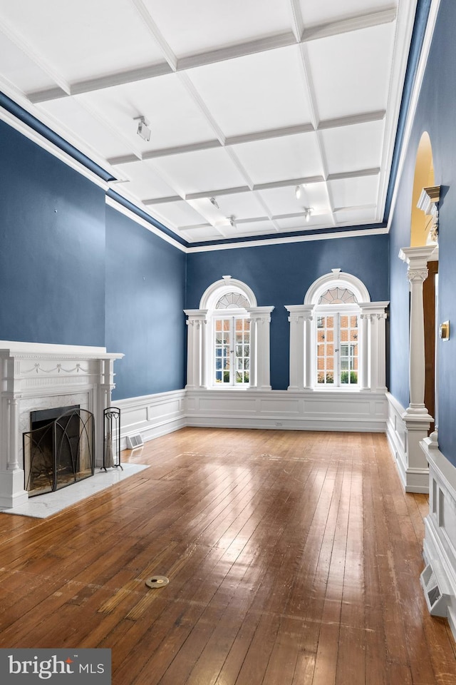 unfurnished living room featuring a high end fireplace, a healthy amount of sunlight, coffered ceiling, and hardwood / wood-style floors