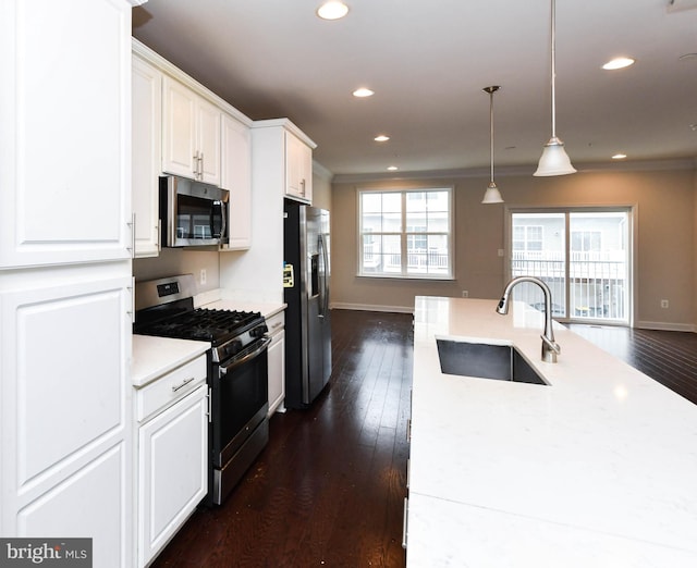 kitchen featuring pendant lighting, sink, appliances with stainless steel finishes, white cabinetry, and dark hardwood / wood-style floors